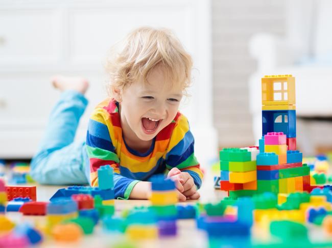 Child playing with colorful toy blocks. Little boy building tower at home or day care. Educational toys for young children. Construction block for baby or toddler kid. Mess in kindergarten play room.