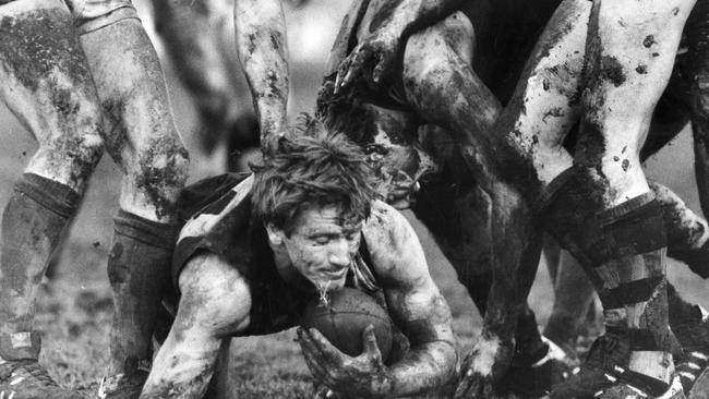 Glenelg's Chris McDermott ploughs through a sea of mud and a forest of legs against Norwood in 1986. Picture: Stuart Hannagan