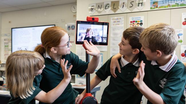 Odinn Meehan’s classmates – Millie O’Connor, Stella Bartholdy, James Moloney and Charlie Moule – give Odinn a wave via his classroom proxy, Odinn 2.0. Picture: David Kelly