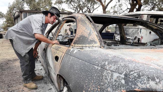 Warren Gosper with his burnt out car. Picture Roger Wyman