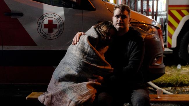 Residents comfort each other near the site where a Russian drone struck a high-rise residential building in Kyiv' on Friday. Picture: AFP