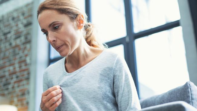 Gradual process. Beautiful mature woman touching sweater and having hot flash