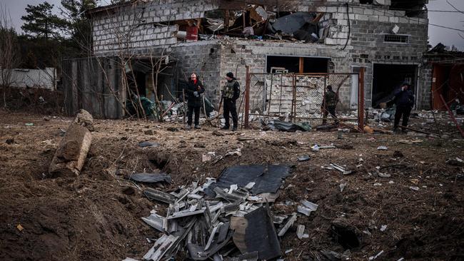 Police officers and residents stand next to a shell crater in front of a house damaged by recent shelling on the outskirts of Kyiv. Picture: AFP