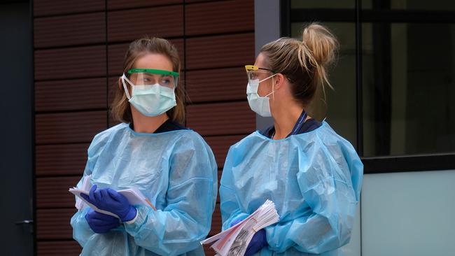 Hospital staff assist people waiting in line to be screened for COVID-19 outside the Royal Melbourne Hospital. Picture: Getty Images