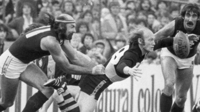 Kevin Bartlett pounces on the loose ball under pressure from Carlton’s Bruce Doull and Val Perovic.