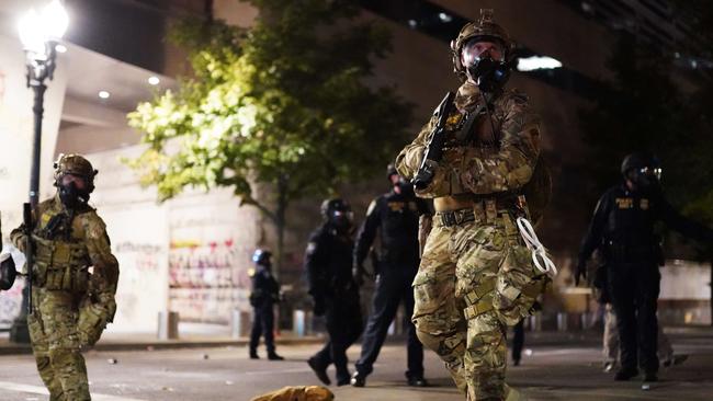 A federal officer watches a crowd of protesters in Portland. Picture: AFP