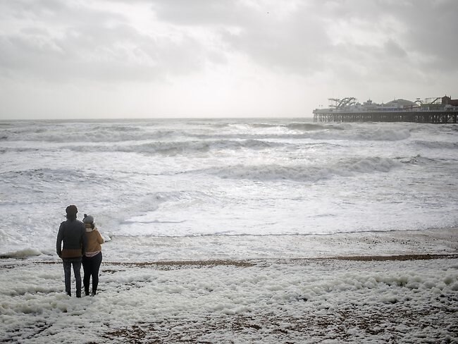 Members of the public brace the stormy weather conditions in Brighton, UK.