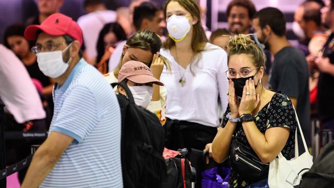 A long queue of passengers waiting to check in for a flight, including some passengers wearing protective face masks at Sydney International Airport, Friday, March 20, 2020. Picture: AAP