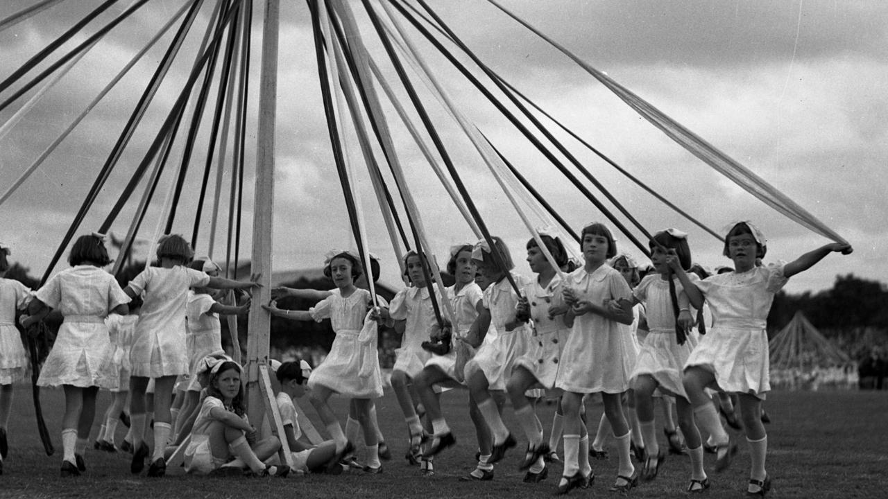 Schoolgirls on the main arena dance around a Maypole, 1937.