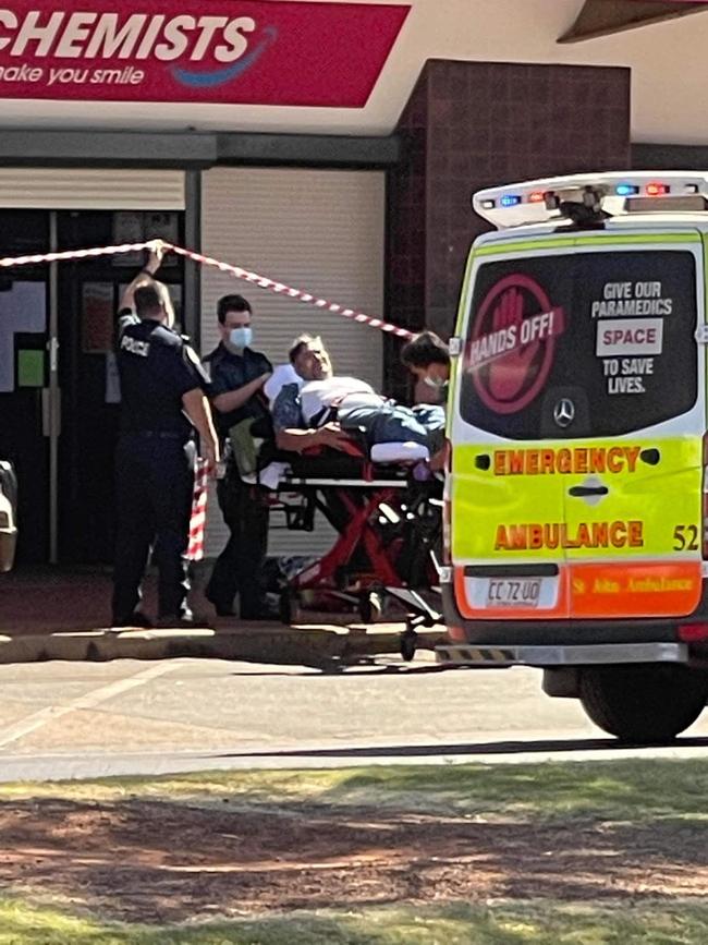 A man is put into an ambulance following an alleged armed robbery at a Tennant Creek pharmacy. Picture: Steve Edgington