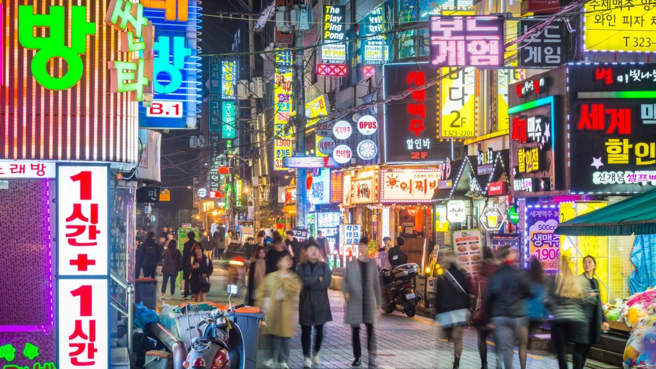 Crowds of people walking through the colourfully illuminated neon night streets of Sinchon, Seoul, South Korea. Picture: iStock