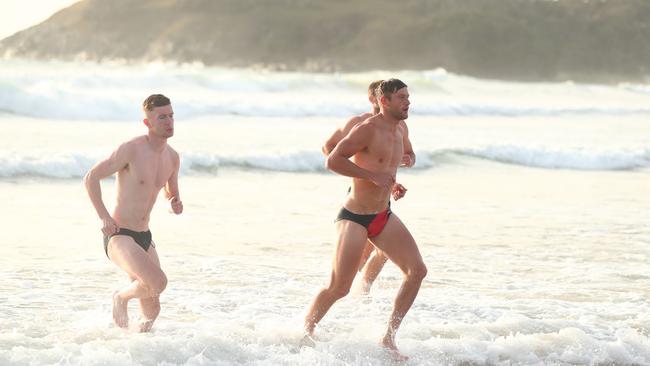 Essendon players return to the beach after a swim.