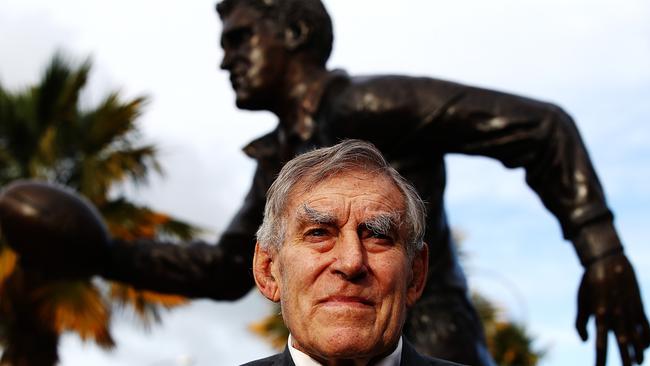 All Blacks great Sir Colin Meads is seen in front of a new statue of himself.