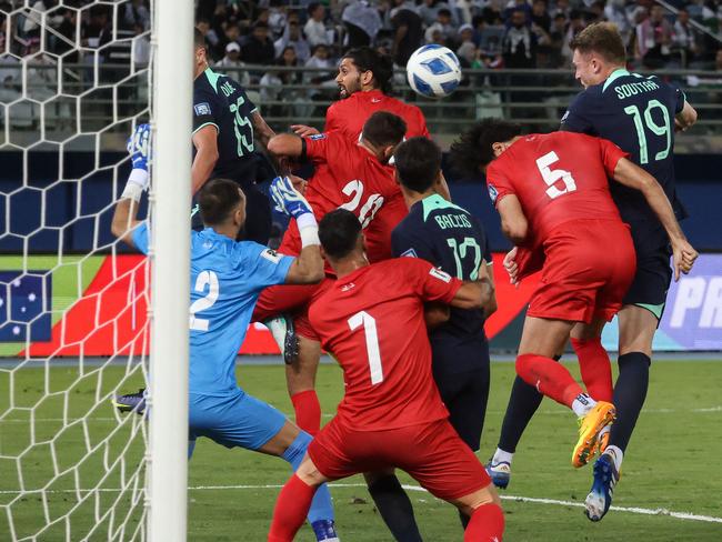 Harry Souttar (right) heads the Socceroos into the lead against Palestine. Picture: Yasser Al-Zayyat / AFP