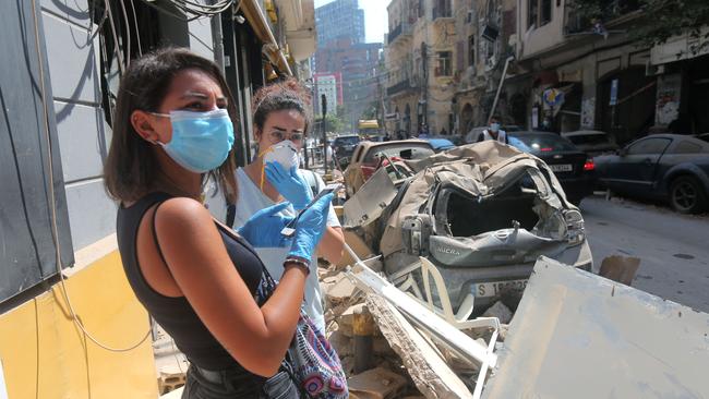 Young Lebanese women stand amid the rubble in Beirut's Gimmayzeh commercial district. Picture: STR/AFP