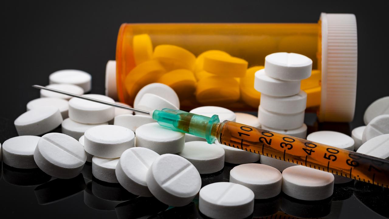 Opioid epidemic and drug abuse concept with a heroin syringe or other narcotic substances next to a bottle of prescription opioids. Oxycodone is the generic name for a range of opioid painkillers.