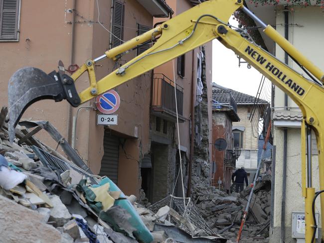 An excavator digs through rubble of collapsed buildings following an earthquake, in Amatrice, Italy. Picture: Alessandra Tarantino.