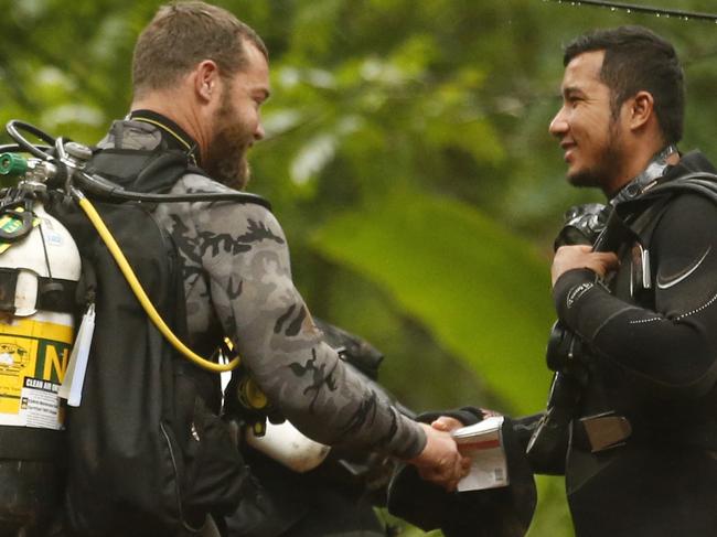 In this Tuesday, July 3, 2018, file photo, Australian Federal Police and Defense Force personnel talk with a Thai diver after the 12 boys and their soccer coach were found alive in a flooded cave in Mae Sai, Chiang Rai province, northern Thailand. (AP Photo/Sakchai Lalit)