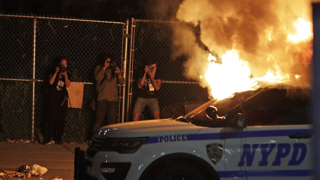 Photographers take pictures of a burning police car in the Brooklyn borough of New York. Picture: AP