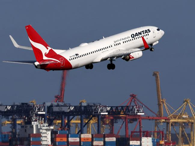 This picture taken on December 6, 2023 shows a Qantas Airways Boeing 737-800 passenger aircraft taking off at Sydneyâs Kingsford Smith international airport in front of a container ship berthed at the Port Botany container terminal. (Photo by DAVID GRAY / AFP)