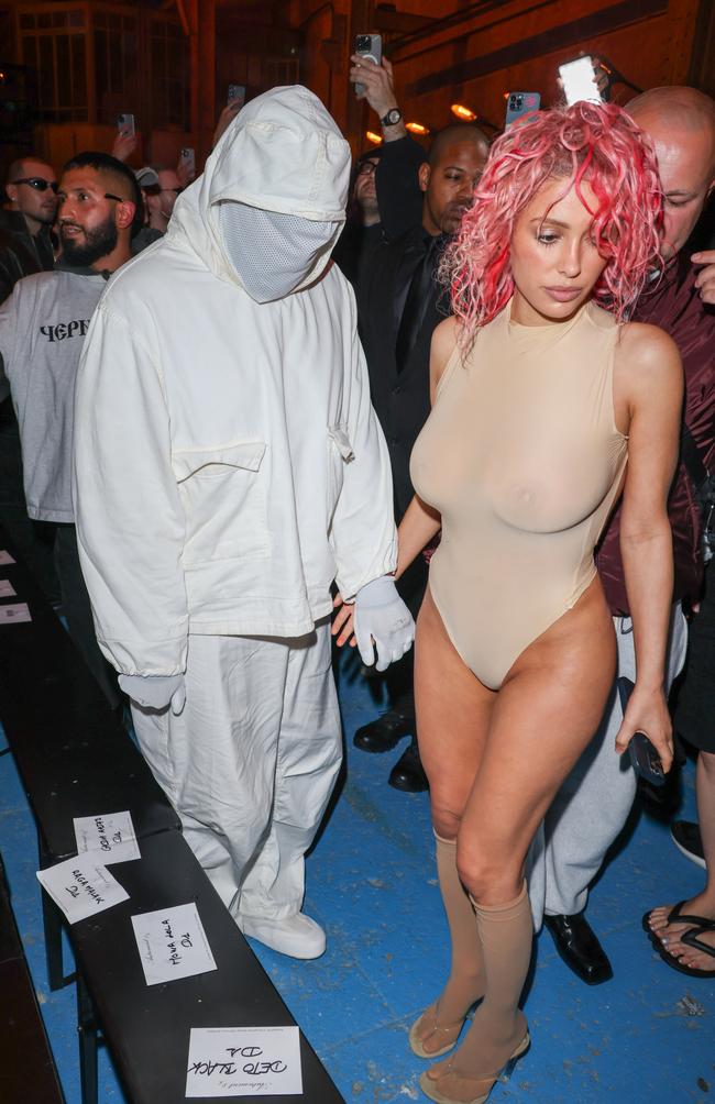 Kanye West hides his face with wife Bianca Censori who sports pink hair and not much else as part of Paris Fashion Week last week. Picture: Peter White/Getty Images