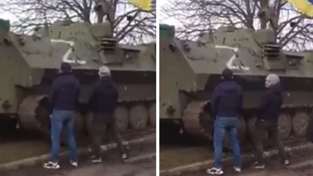 Ukrainian men are seen urinating on a Russian tank with the Z symbol on it.