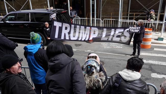 Demonstrators hold a banner in front a group of journalists outside of the Criminal Courts Building as the grand jury continues to hear evidence against the former president.