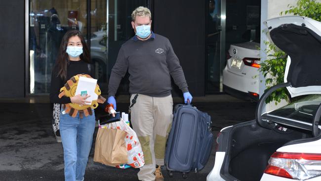 A staff member assists a woman leaving quarantine from the IBIS hotel in the city on Saturday. Picture: Brenton Edwards