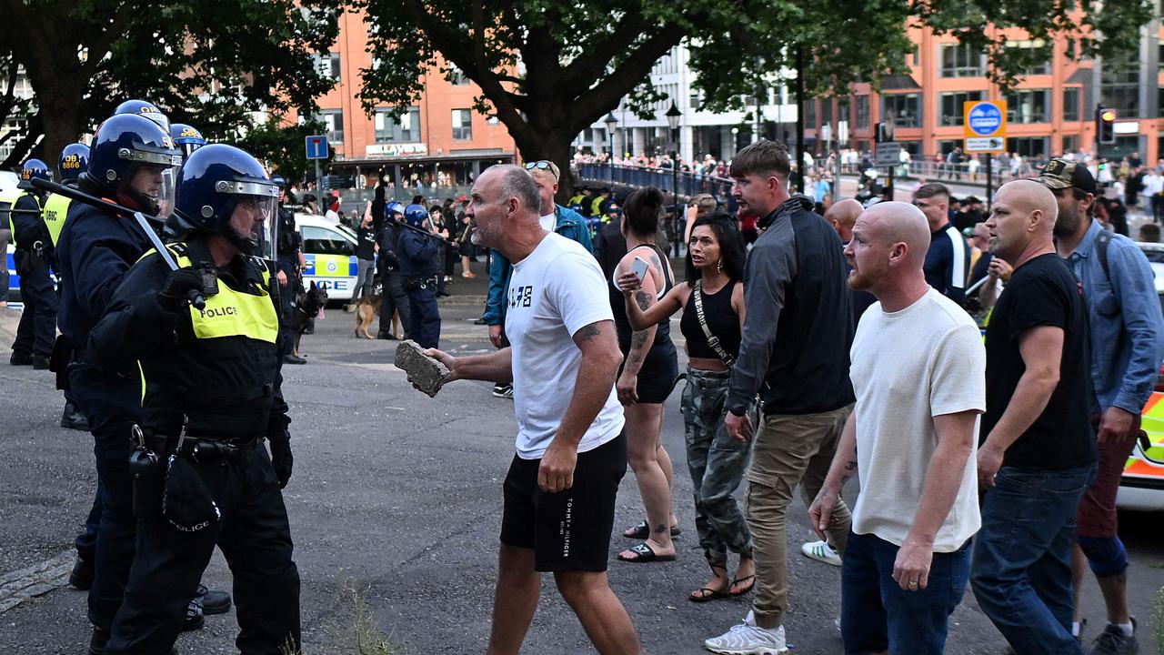 A protester holding a piece of concrete walks towards riot police as clashes erupt in Bristol in southern England. Picture: Justin Tallis / AFP