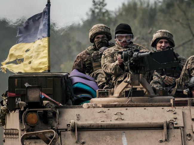 TOPSHOT - Ukrainian soldiers ride on an armoured vehicle near the recently retaken town of Lyman in Donetsk region on October 6, 2022, amid the Russian invasion of Ukraine. - The people of Lyman, emerging from cellars after Ukraine recaptured the town from Russian forces, have been left confused and fearful by both the battle and the shifting political map. Lyman is in Ukrainian hands and the sounds of explosions come from de-mining teams performing controlled detonations in the pine forests that surround Lyman, polluted by the debris of war. (Photo by Yasuyoshi CHIBA / AFP)