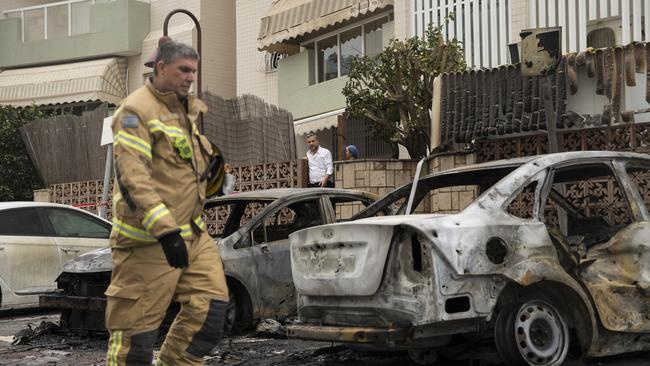 An Israeli fire fighter walks through the aftermath of burned cars after a rocket fired from the Gaza Strip hit Ashdod. Picture: Getty Images