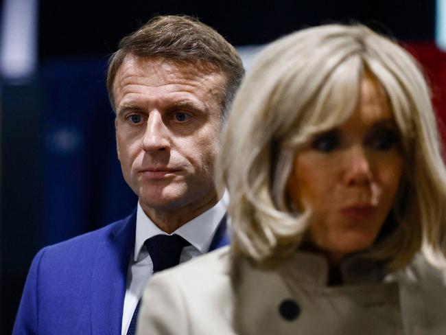 French President Emmanuel Macron (L) and his wife Brigitte Macron walk prior to cast their vote in the first round of parliamentary elections at a polling station in Le Touquet, northern France on June 30, 2024. A divided France is voting in high-stakes parliamentary elections that could see the anti-immigrant and eurosceptic party of Marine Le Pen sweep to power in a historic first. The candidates formally ended their frantic campaigns at midnight June 28, with political activity banned until the first round of voting. (Photo by Yara Nardi / POOL / AFP)