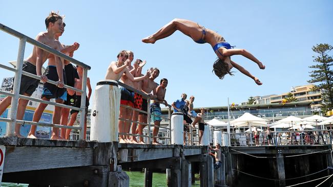 Jess Schmidt, 14, being cheered on by friends as she does a backflip off Manly Wharf into the water. Picture: Tim Hunter