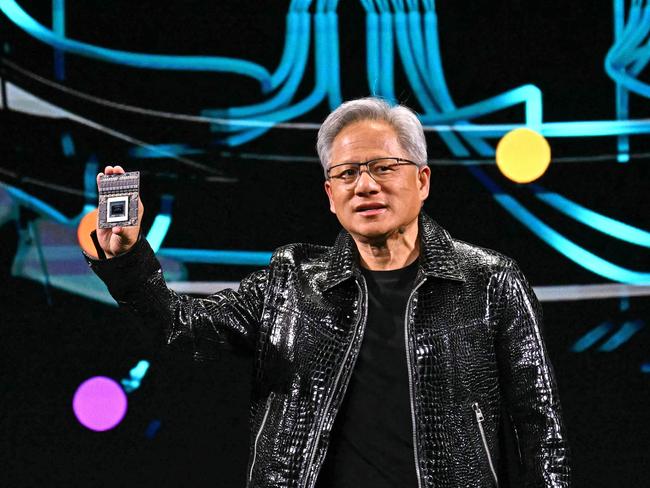 Nvidia CEO Jensen Huang holds a Nvidia's Drive Thor processor as he delivers a keynote address at the Consumer Electronics Show (CES) in Las Vegas, Nevada on January 6, 2025. Gadgets, robots and vehicles imbued with artificial intelligence will once again vie for attention at the Consumer Electronics Show, as vendors behind the scenes will seek ways to deal with tariffs threatened by US President-elect Donald Trump. The annual Consumer Electronics Show (CES) opens formally in Las Vegas on January 7, 2025, but preceding days are packed with product announcements. (Photo by Patrick T. Fallon / AFP)