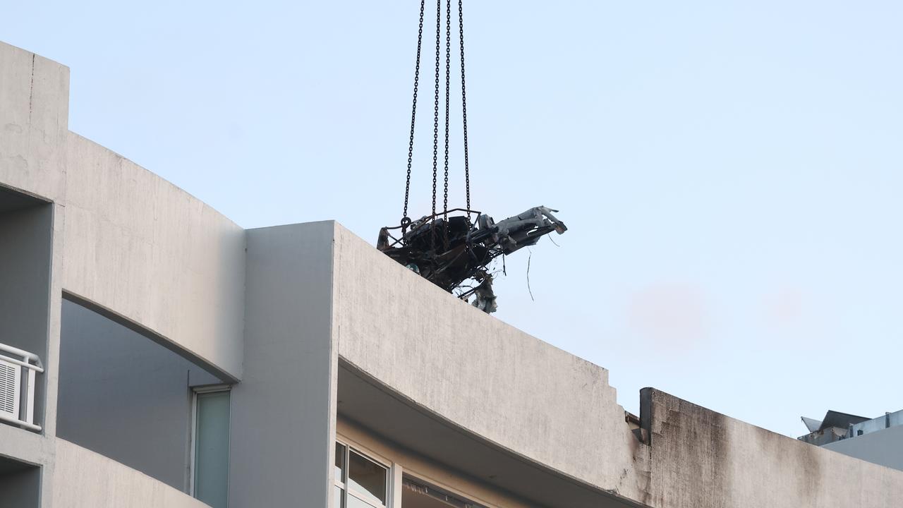 A large crane lifts the wreckage of a Robinson R44 helicopter off the roof top of the Double Tree Hilton hotel into a skip bin, before lowering it to the Cairns Esplanade. The chopper was stolen from Nautilus Aviation and crashed onto the roof at about 1:50am on Monday. Picture: Brendan Radke