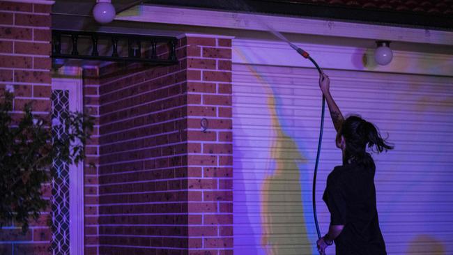 A Wattle Grove resident hosing down their home overnight. Picture: Darren Leigh Roberts