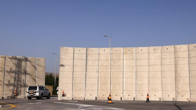 A vehicle moves along a road past newly-erected concrete blast barriers at a position in the Upper Galilee region in northern Israel near the border with southern Lebanon.