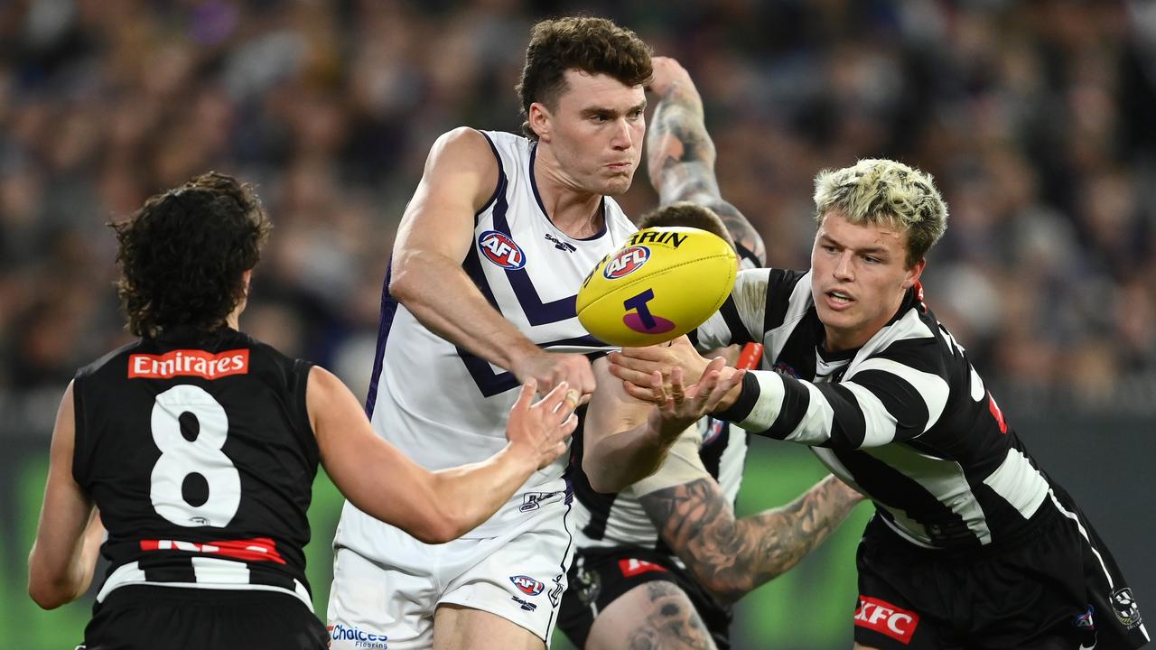 Blake Acres of the Dockers handballs whilst being tackled by Jack Ginnivan of the Magpies. Picture: Quinn Rooney
