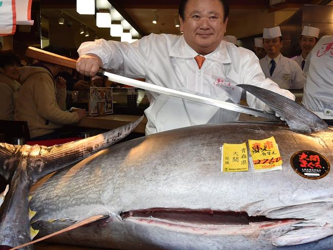 Kiyoshi Kimura (C), president of Kiyomura Corp., the Tokyo-based operator of sushi restaurant chain Sushizanmai, poses with a sword before slicing up a bluefin tuna the company bought for 193.2 million yen (1.8 million USD) at auction at his main restaurant in Tokyo on January 5, 2020. - Kiyomura Corp. made the winning bid of 1.8 million USD for a 276-kilogram bluefin tuna caught off Oma, Aomori prefecture at the first auction of the year earlier in the day at Tososu fish market. (Photo by Kazuhiro NOGI / AFP)