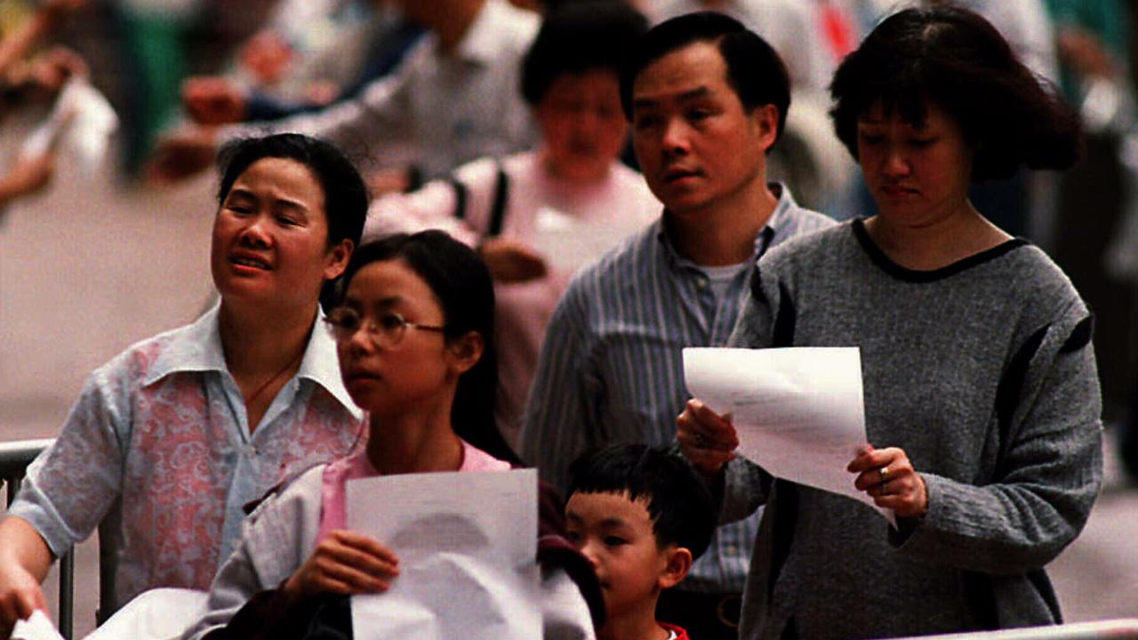 Hong Kong residents holding registration forms, queue to apply for British National Overseas passports in 1996.