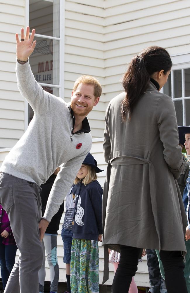 Prince Harry waves to fans as he and Meghan meet with students from Houghton Valley School. Picture: Mark Mitchell/AP