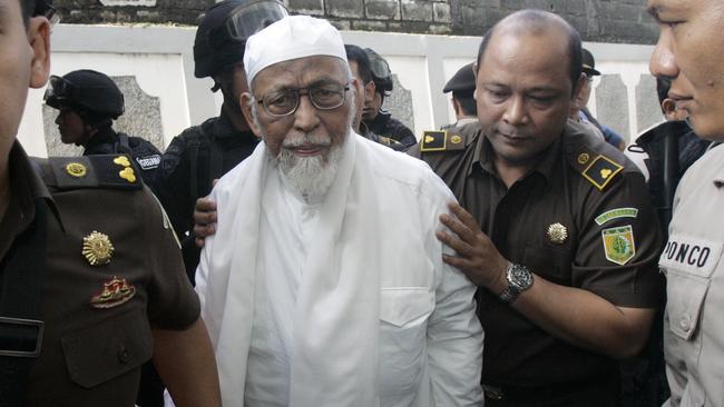 Radical cleric Abu Bakar Bashir is escorted by prosecutors and police officers upon arrival for his trial at a district court in Jakarta, Indonesia, in 2011. Picture: AP