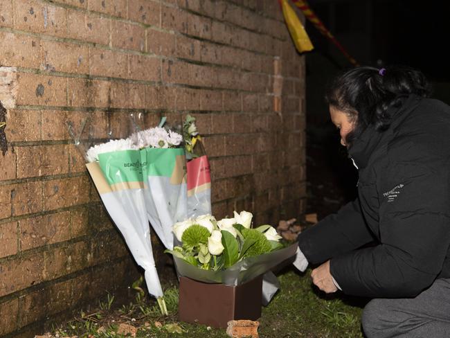 A woman lays flowers at the scene of the fire on Sunday. Picture: Monique Harmer