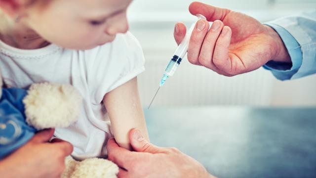 Doctor pediatrician injecting vaccine to cute  girl