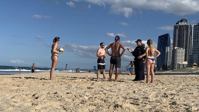 Police speak to a group of German students playing volleyball on Surfers Paradise beach. Picture: Ryan Keen.