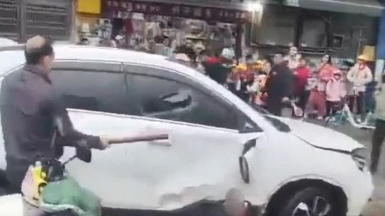 A man breaks the window of a car that drove into a group of children outside a Changde primary school in a screengrab from footage posted to social media. Picture: Weibo