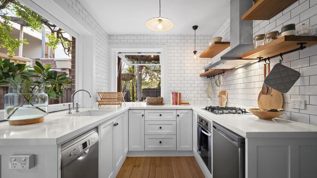 Stone-topped kitchen benches and, nearby, a dining area backed by subway tiles – a style of rectangular tiles that are usually laid horizontally.