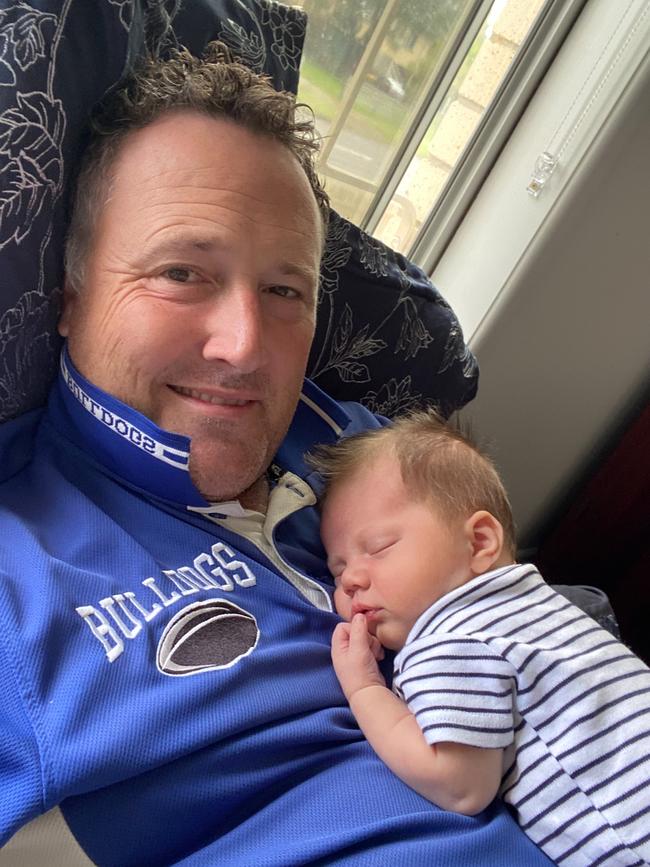 David doing round 19 SuperCoach research while holding newborn Elijah.