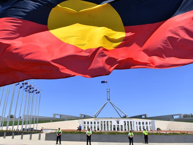 A marcher holds a flag as he protests for Aboriginal rights on Australia Day at Parliament House in Canberra, Sunday, January 26, 2020. (AAP Image/Mick Tsikas) NO ARCHIVING