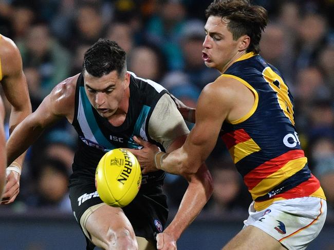 Port Adelaide’s Tom Rockliff gets a kick away despite pressure from Crow Jake Kelly during Showdown 46. PHOTO: AAP Image/David Mariuz